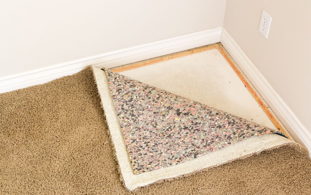 Carpet padding being tacked down onto concrete flooring.