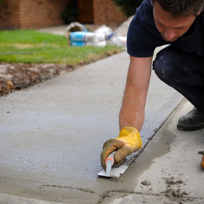 A man working on creating a concrete driveway.