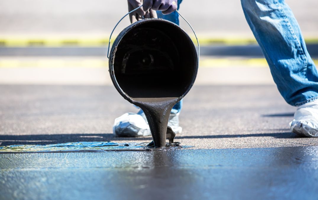 Sealer being poured on top of a concrete driveway.