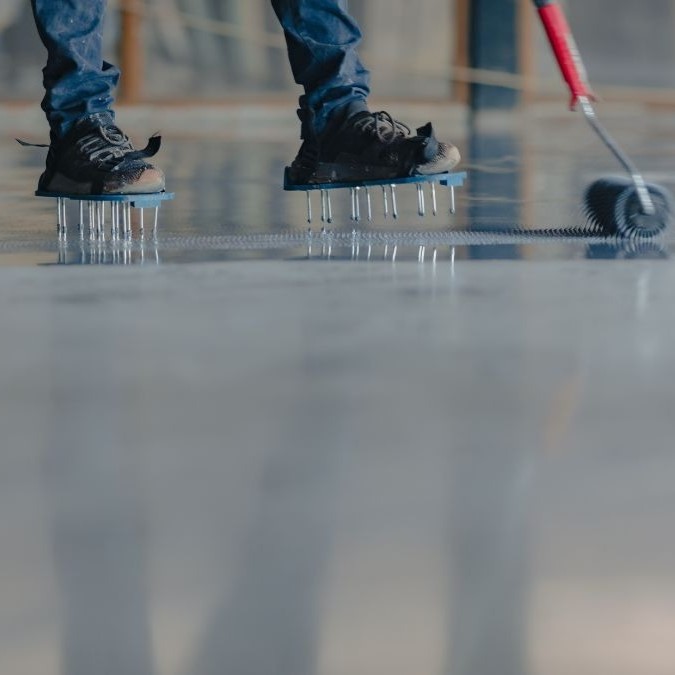 An epoxy coating being rolled onto a concrete floor base.