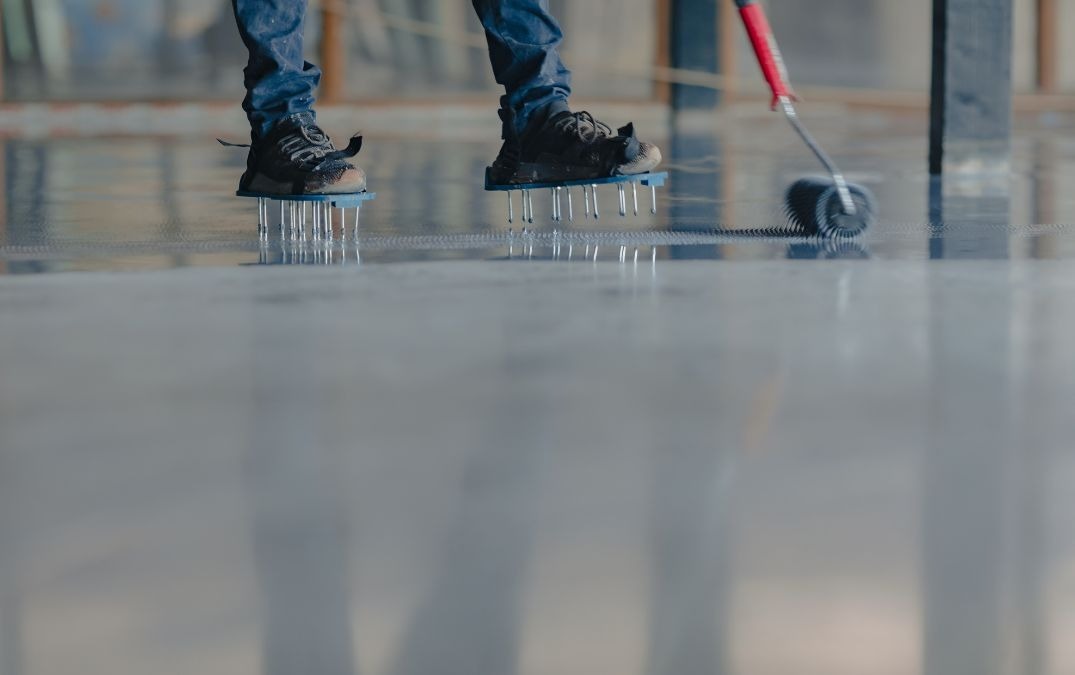 An epoxy coating being rolled onto a concrete floor base.