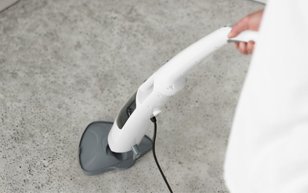 A steam mop being used on a concrete floor.