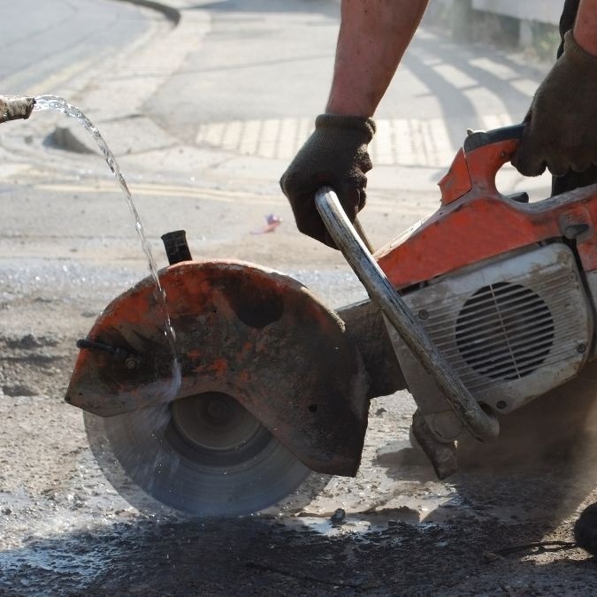 Angle grinder being used to remove concrete flooring.