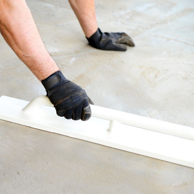 A man preparing a concrete floor for laminate laying.