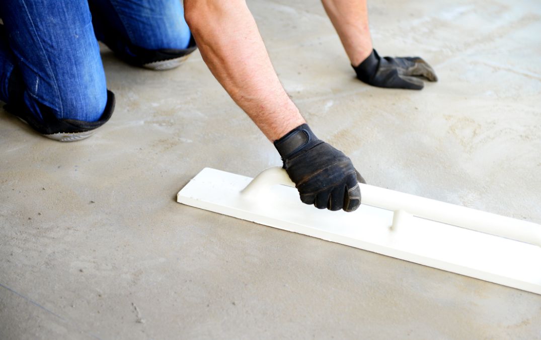 A man preparing a concrete floor for laminate laying.