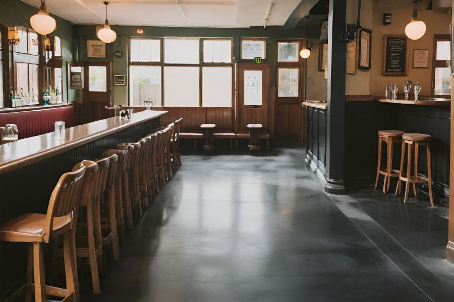 A pub with a sleek black polished concrete floor with wooden stools in Exeter