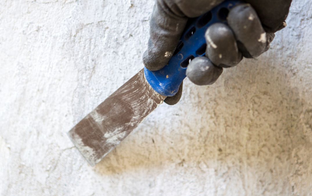 A scraper being used to remove paint from a concrete floor.