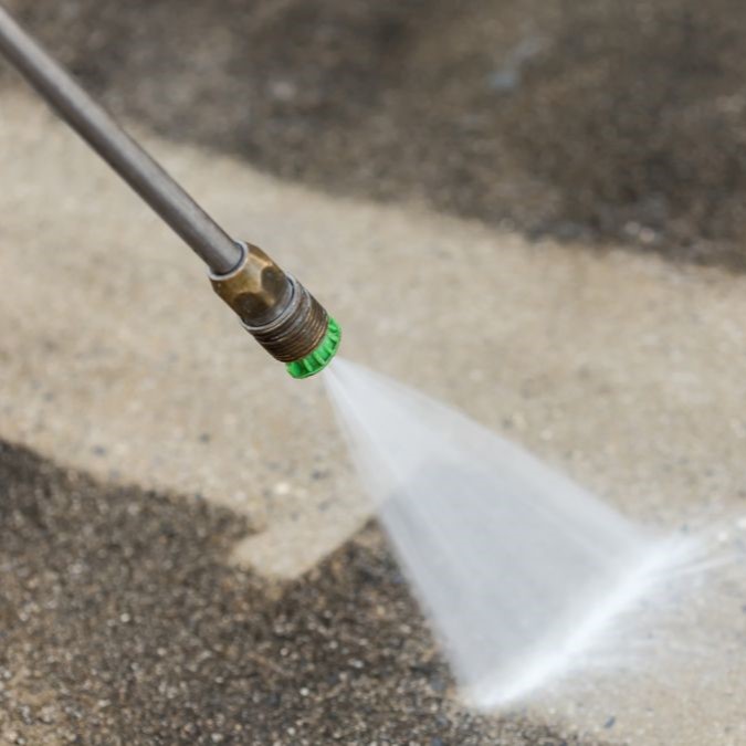 A man preparing a concrete floor to be sealed by jet washing it