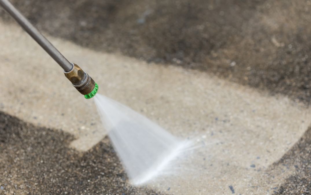 A man preparing a concrete floor to be sealed by jetwashing it