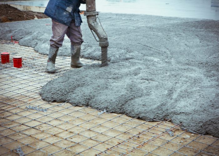 pouring concrete mix into a foundation with mesh reinforcement