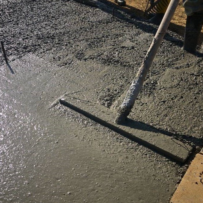 A bull float being used to smooth wet concrete.