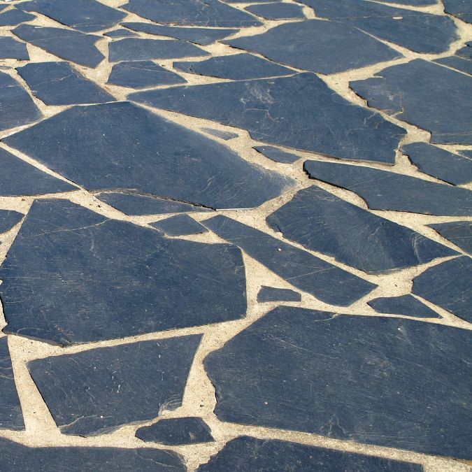 Mismatched slate flooring in a garden, various shapes and patterns.