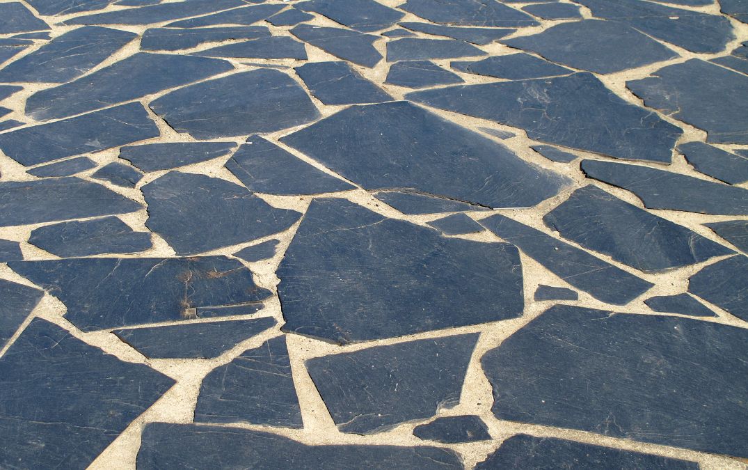 Mismatched slate flooring in a garden, various shapes and patterns.