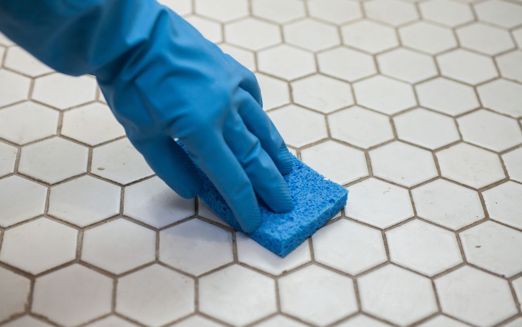 Grout on a tile floor being scrubbed clean.