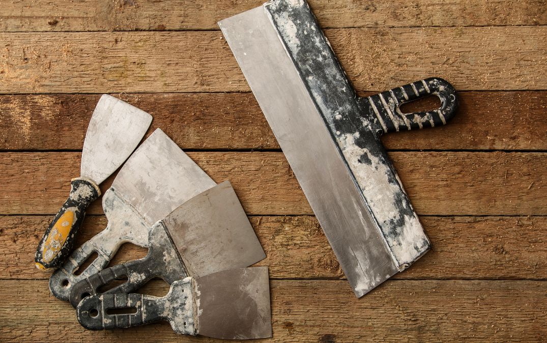 Putty knife and scrapers for removing cement from floor tiles.