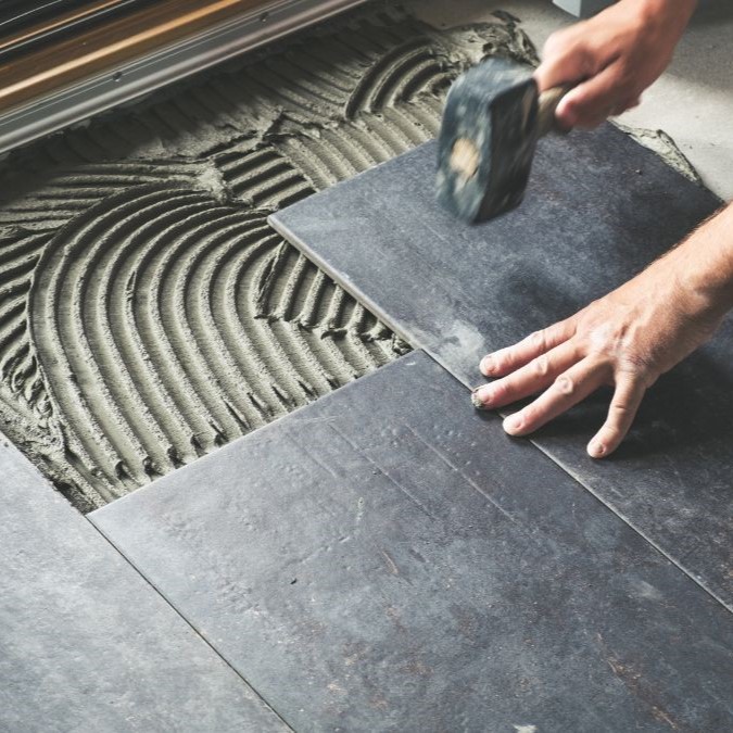 Tile flooring being tapped down into its adhesive.