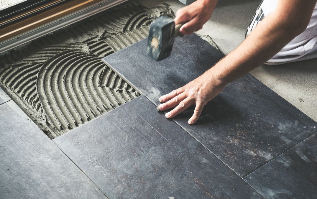 Tile flooring being tapped down into its adhesive.